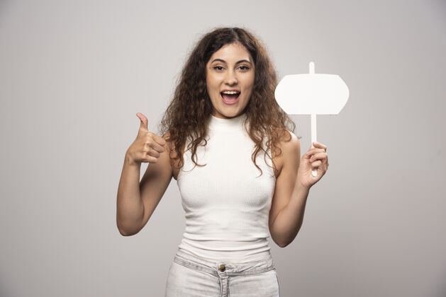 脸一位年轻女士举着大拇指 举着一张白色的空白海报高质量的照片青少年女性长相