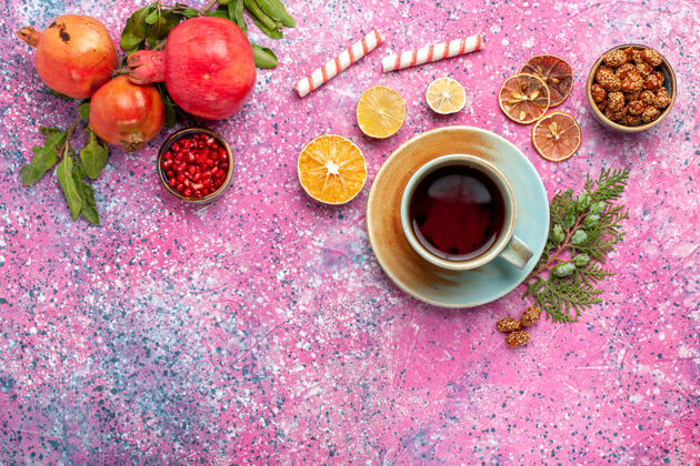 顶部在粉红色的桌子上 可以俯瞰新鲜的石榴 绿叶和一杯茶石榴闪亮庆典
