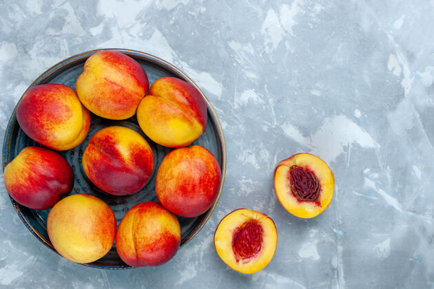 油桃在浅白色的桌子上俯瞰新鲜成熟的桃子和美味的夏季水果桃子食物生的