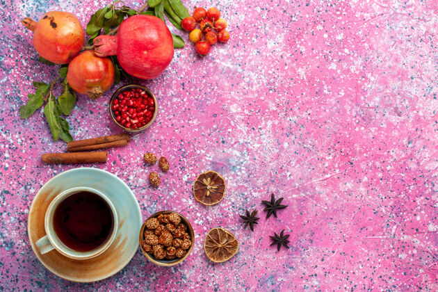 茶顶视图新鲜石榴与绿叶和一杯茶在粉红色的表面草莓食物醇香