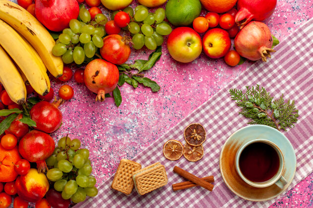 醇香的顶视图新鲜水果组成五颜六色的水果与一杯茶和华夫饼在粉红色的表面华夫饼多汁的维生素