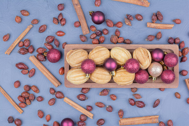 球传统的胡桃饼干放在木制盘子里 还有圣诞装饰奶油精致糕点