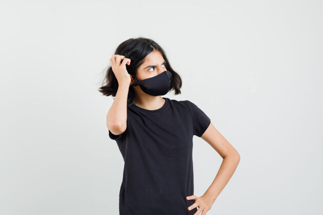 漂亮穿着黑色t恤的小女孩 戴着面具搔着头 神情沉思 前视图青少年刮擦女孩