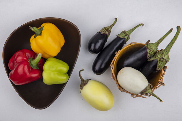 胡椒顶视图白色和黑色茄子在一个篮子里 彩色甜椒在一个白色背景的碗里茄子颜色铃铛