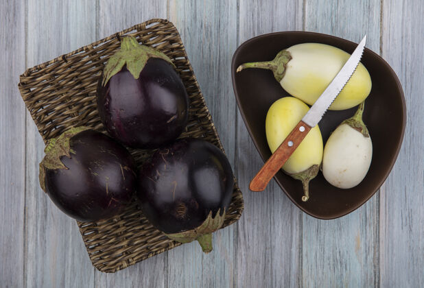 白的篮子里的茄子俯视图 黄色和白色的茄子在木制背景上 碗里有刀茄子木头蔬菜