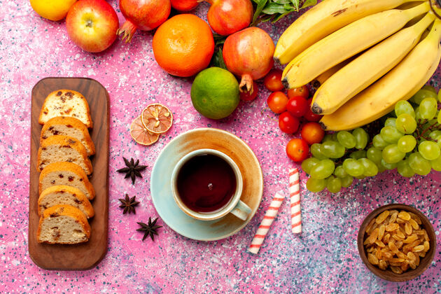 异国情调俯瞰美味的水果组成与切片蛋糕在粉红色的办公桌上醇香苹果饼干