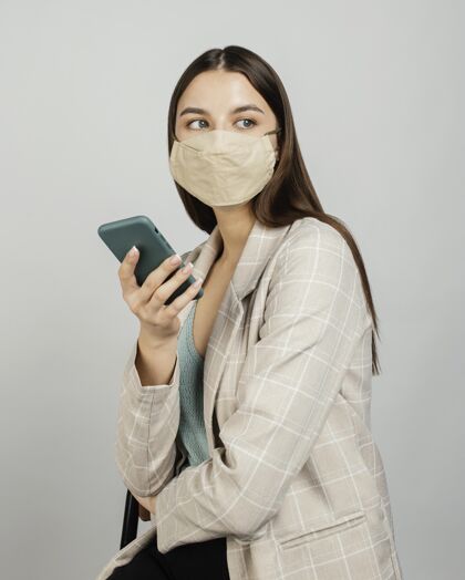 电话肖像时尚的女人用手机带面具预防防护手机