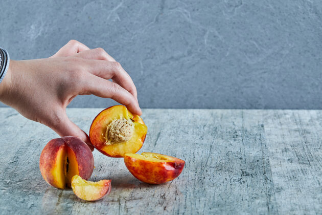 有机手拿着半块桃子放在大理石表面生健康食物