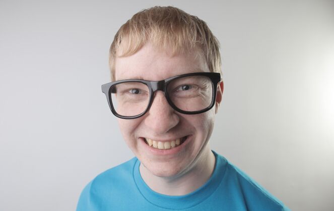 光学特写镜头中 一位身穿蓝色t恤 戴着眼镜的白人男性做着滑稽的面部动作鼻子幽默眼镜