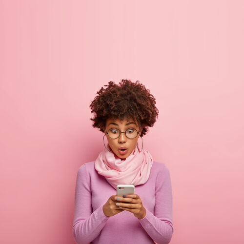 恍惚惊骇的黑皮肤千禧一代女性通过智能手机查看邮件 有惊骇的表情 上网发送眼镜媒体