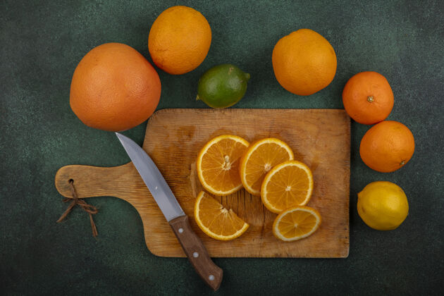 水果俯瞰切菜板上的橙子和刀子柠檬酸橙和柚子的绿色背景橙色板五颜六色