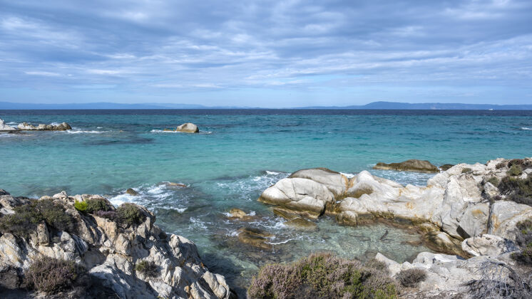 岩石四周绿树成荫的爱琴海海岸 岩石和灌木 碧波荡漾的海水 希腊悬崖海景地中海