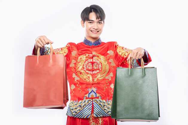 红色穿旗袍西服的男人微笑着从中国新年购物纸袋购物信用卡纸袋