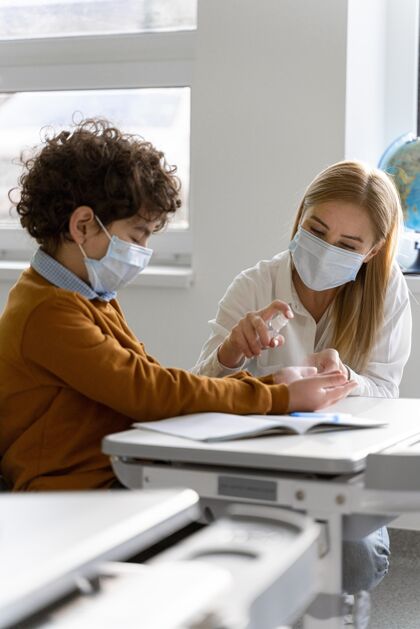 垂直女老师带着医用口罩在课堂上给学生的手消毒流行病教师知识