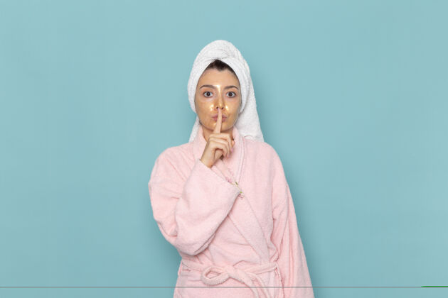 女性前视图：年轻女性 穿着粉色浴袍 淋浴后 蓝色墙壁上有安静的标志 美丽的水霜 自我护理淋浴浴室人尺子后面