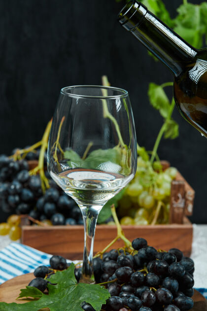季节一盘各种葡萄配一杯白葡萄酒放在白桌子上配酒瓶水果杯子甜的
