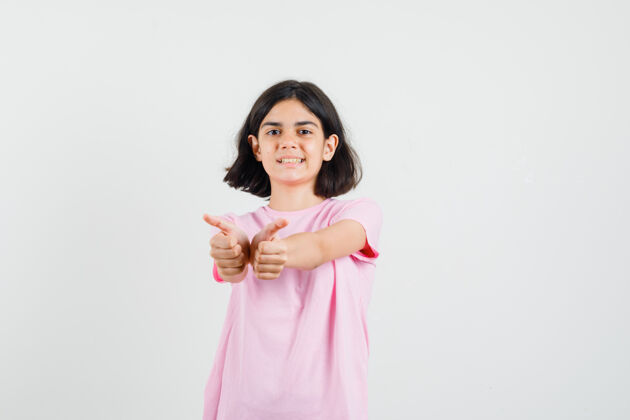 向上穿着粉色t恤的小女孩向上竖起大拇指 看上去很高兴 正面照年轻显示年轻