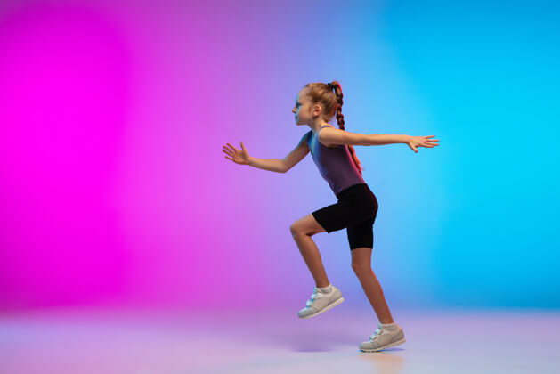 专业健康少女 专业跑步者 慢跑者 在霓虹灯下的渐变粉蓝色背景上运动隔离运动 运动 活力和动态的概念 健康的生活方式训练霓虹灯运动员