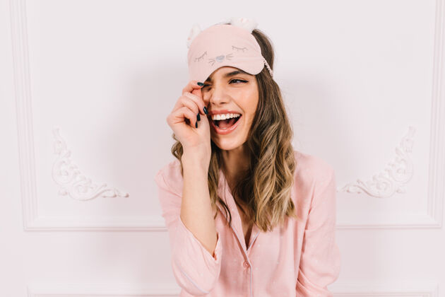 快乐穿着粉色睡衣的漂亮女人在墙上摆姿势时尚幸福面具