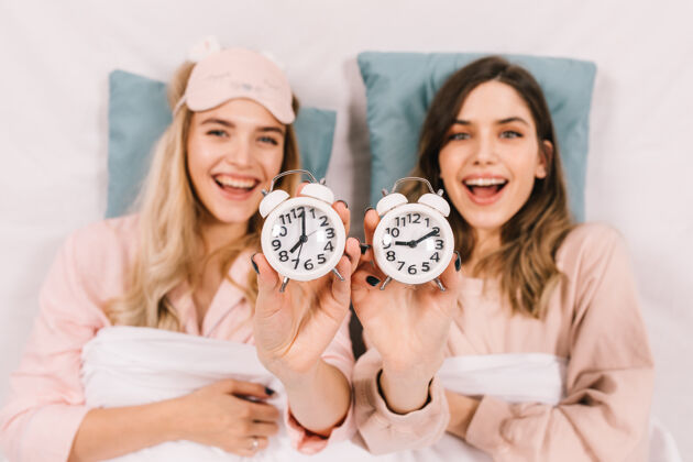 生活方式热情的女人在床上展示钟表笑话友谊女人
