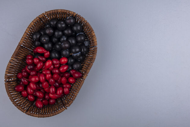 树懒顶视图的水果 如山茱萸和树莓在篮子里的灰色背景与复制空间空间灰色浆果