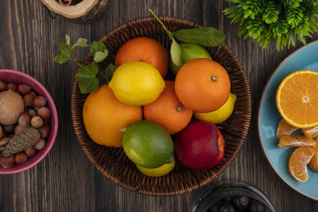 橘子顶视图水果混合在篮子橙子柠檬酸橙和桃子在木制背景上顶部酸橙柠檬