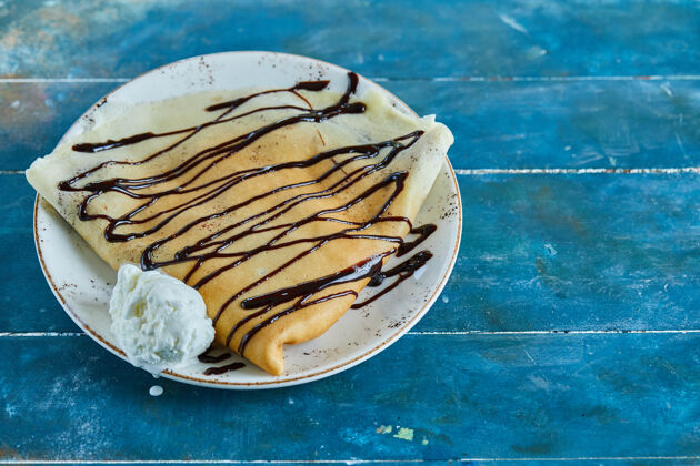 冰淇淋球薄煎饼配香草冰淇淋 巧克力放在蓝色的白色盘子里香精美味的吃的
