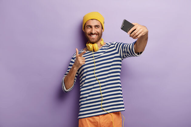 风格年轻快乐的男人自拍 打视频电话 指着智能手机的摄像头现代积极移动
