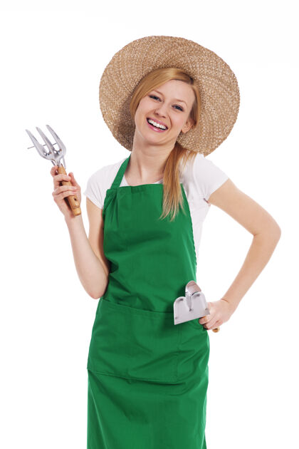 表达积极性手持园艺设备的女农民大笑帽子站立