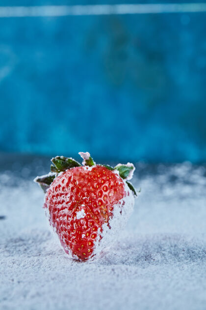 成熟新鲜的红色草莓在蓝色的表面与粉末水果夏天美味