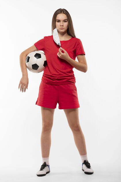 足球戴着面具拿着球的女足球运动员外科面罩足球运动员年轻