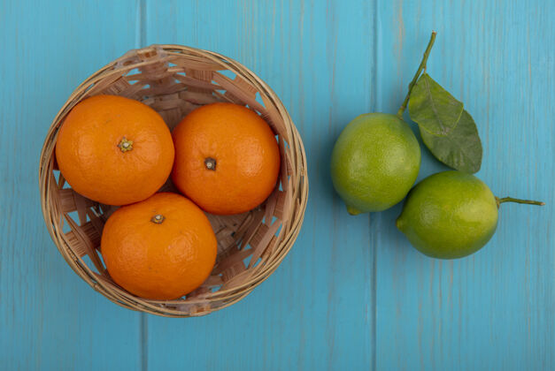 顶部在蓝绿色的背景下 篮子里放着橘子和酸橙橘子水果篮子
