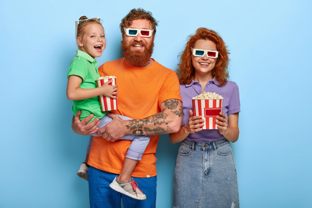 爸爸乐观的三个家庭成员开心地笑着 一起在电影院看喜剧 享受美味的爆米花姿势喜剧一起
