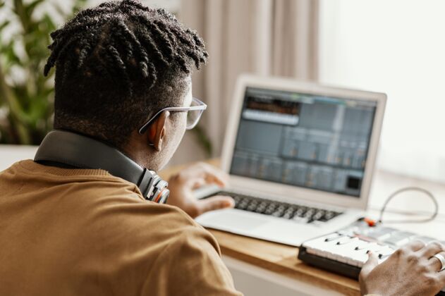 耳机男音乐家在家使用笔记本电脑男人艺术家技能