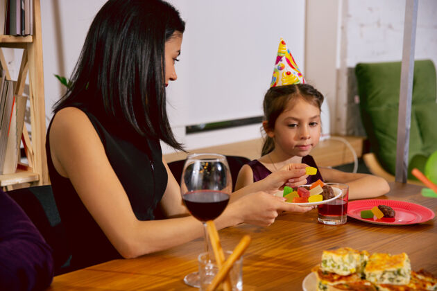 女性母亲和女儿在家里庆祝生日一个大家庭一边吃蛋糕 一边喝酒 一边向孩子们打招呼 玩得开心庆祝 家庭 聚会 家庭 童年 为人父母的理念兄弟气球父母