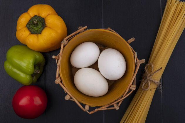 鸡肉顶视图鸡蛋在篮子里与生意大利面和甜椒黑背景营养食物生的