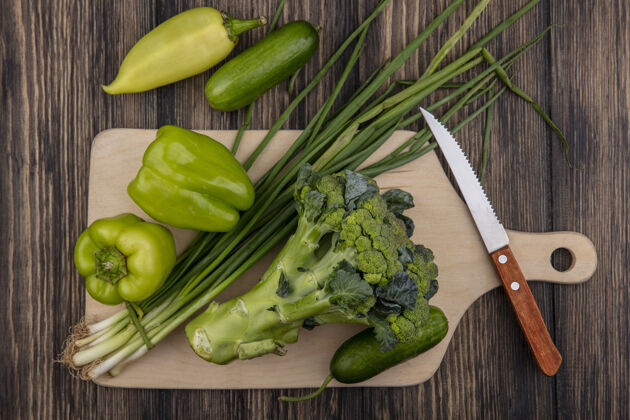 新鲜顶视图黄瓜与青椒花椰菜和葱在砧板上用刀在木制背景西兰花黄瓜刀