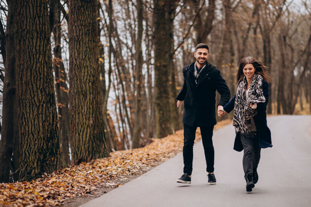 快乐的女人一对年轻夫妇在秋天的公园里散步休闲男朋友快乐