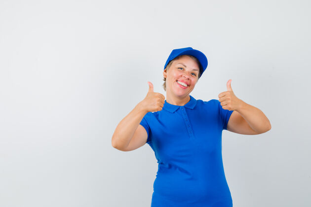 活跃穿蓝色t恤的成熟女人竖起大拇指 看起来很高兴脸帽子女人