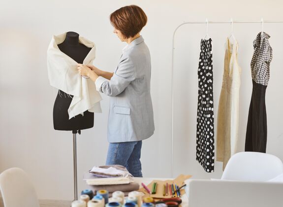 线女时装设计师的侧视图在工作室与服装形式服装商业裁缝