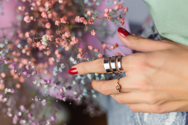 美甲近景拍摄的是戴着两枚戒指的女人手指头 一束五颜六色的干花化妆品成人优雅