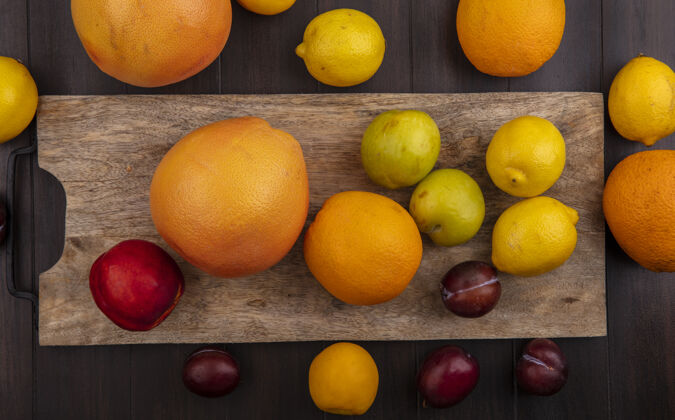 水果在木制背景上的砧板上俯瞰柠檬 橙子 李子 桃子和葡萄柚顶李子木头