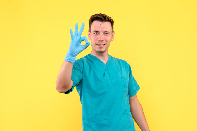 成人黄墙上戴着蓝手套的男医生的正视图手套休闲黄色