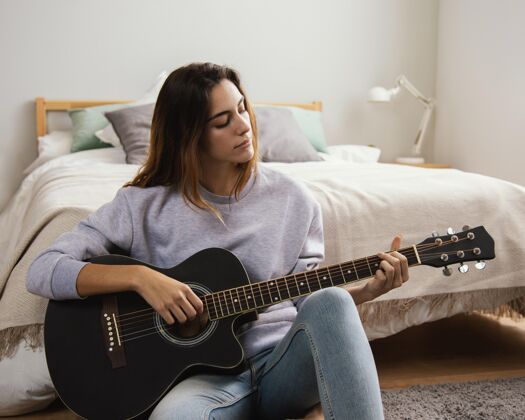 吉他在家弹吉他的年轻女子娱乐住宿室内