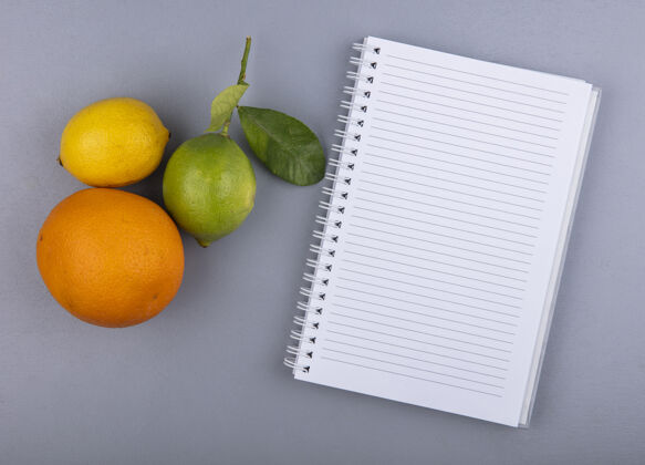 橙色顶视图复制空间记事本与橙色柠檬和石灰的灰色背景灰色笔记本记事本
