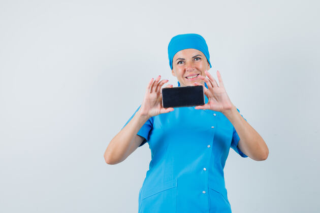 护士女医生穿着蓝色制服在手机上拍照 看起来很有趣前视图手机肖像电话