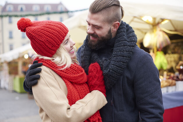 城市生活圣诞集市上的情侣拥抱面对面债券围巾