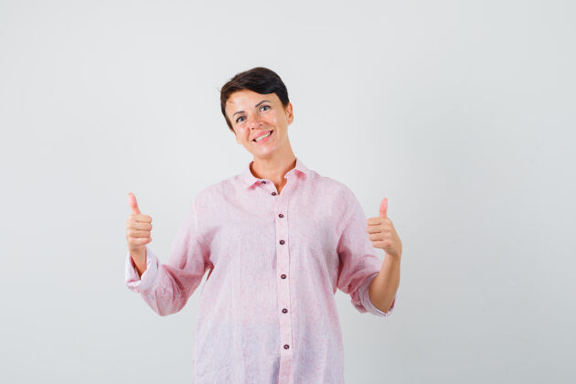 肖像女性穿着粉色衬衫 向上竖起大拇指 看起来很开心 正面视图护士拇指保护