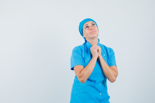 肖像身着蓝色制服的女医生双手合十 做着祈祷的姿势 看上去充满希望 正前方的景色制服扣预防