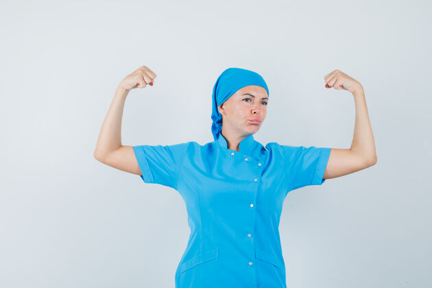 肖像女医生穿着蓝色制服展示手臂肌肉 看上去很自信前视图治疗职员表演